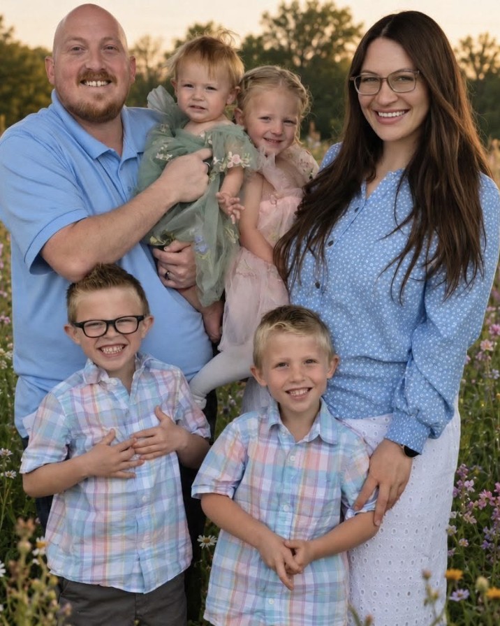 Zandra with her husband and their four children, standing in a field of wildflowers